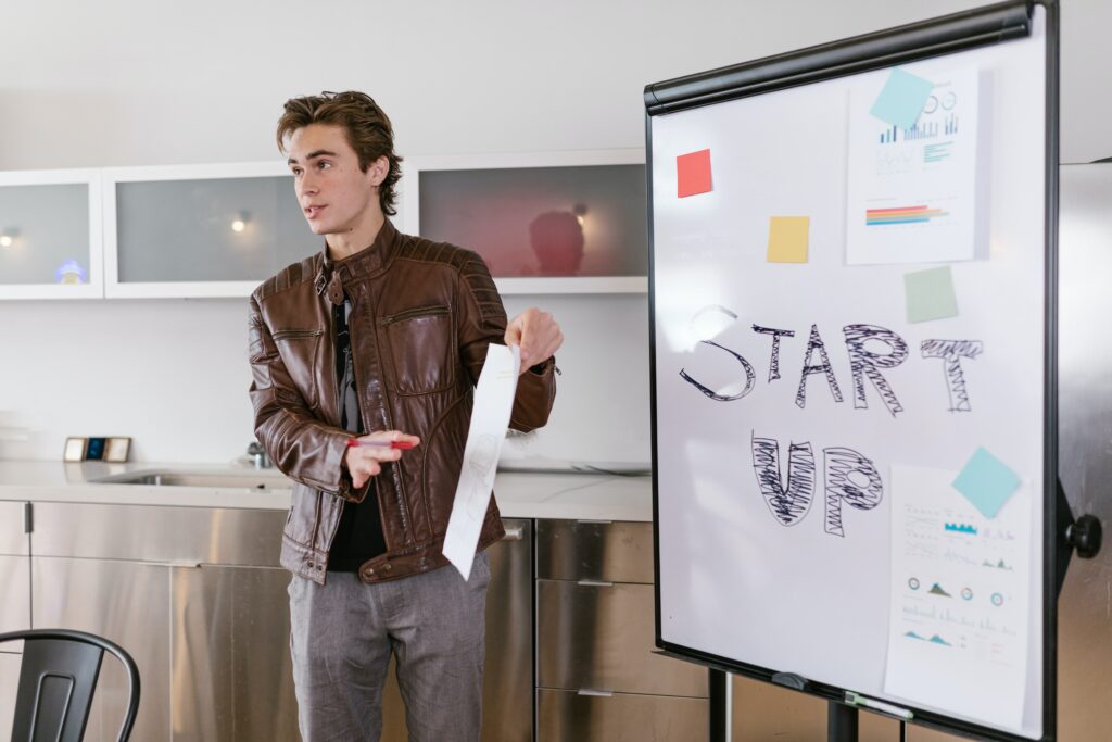 jeune homme devant un tableau blanc où il y a écrit start up